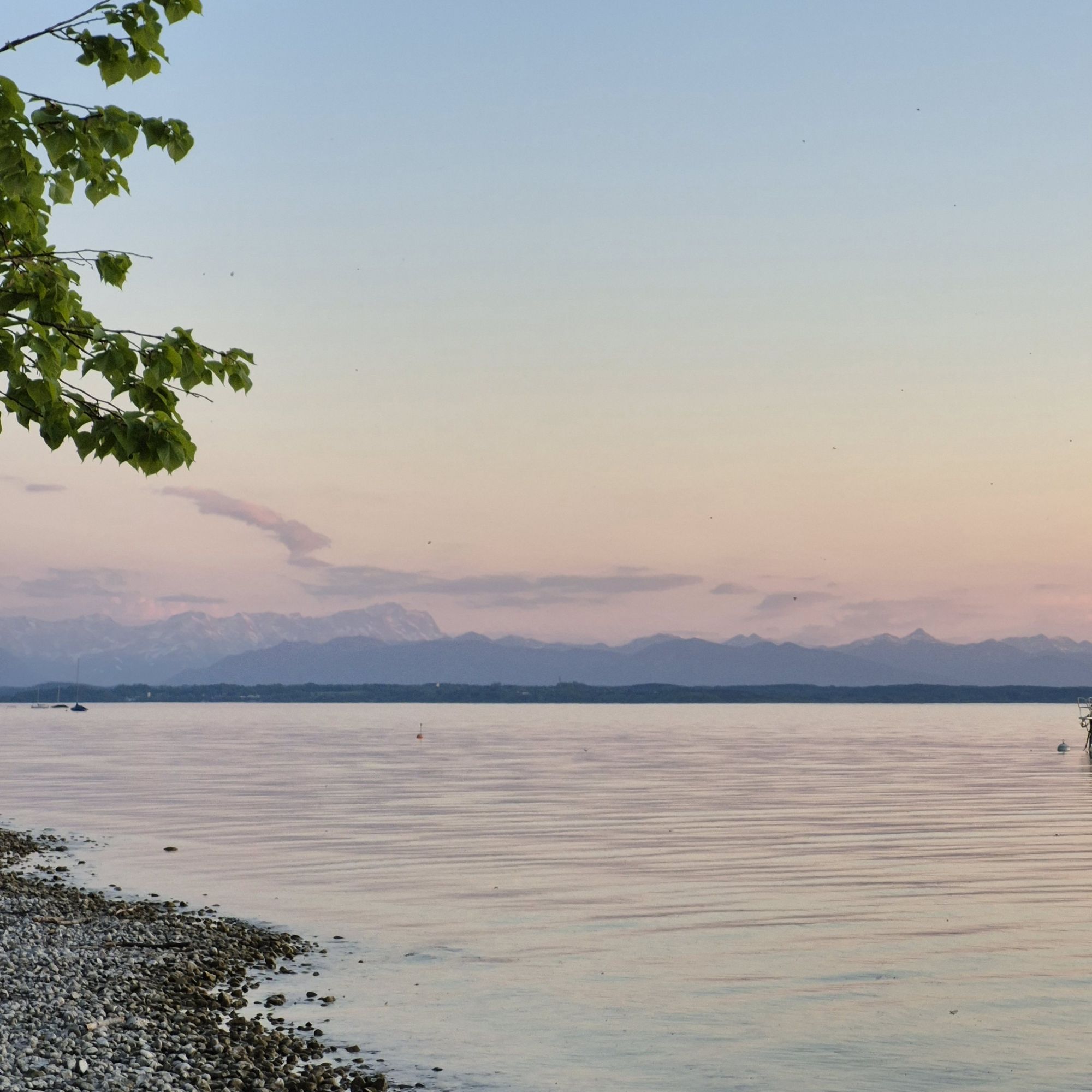 Blick über den Starnberger See mit Gebirgskette und Zugspitze im Hintergrund.