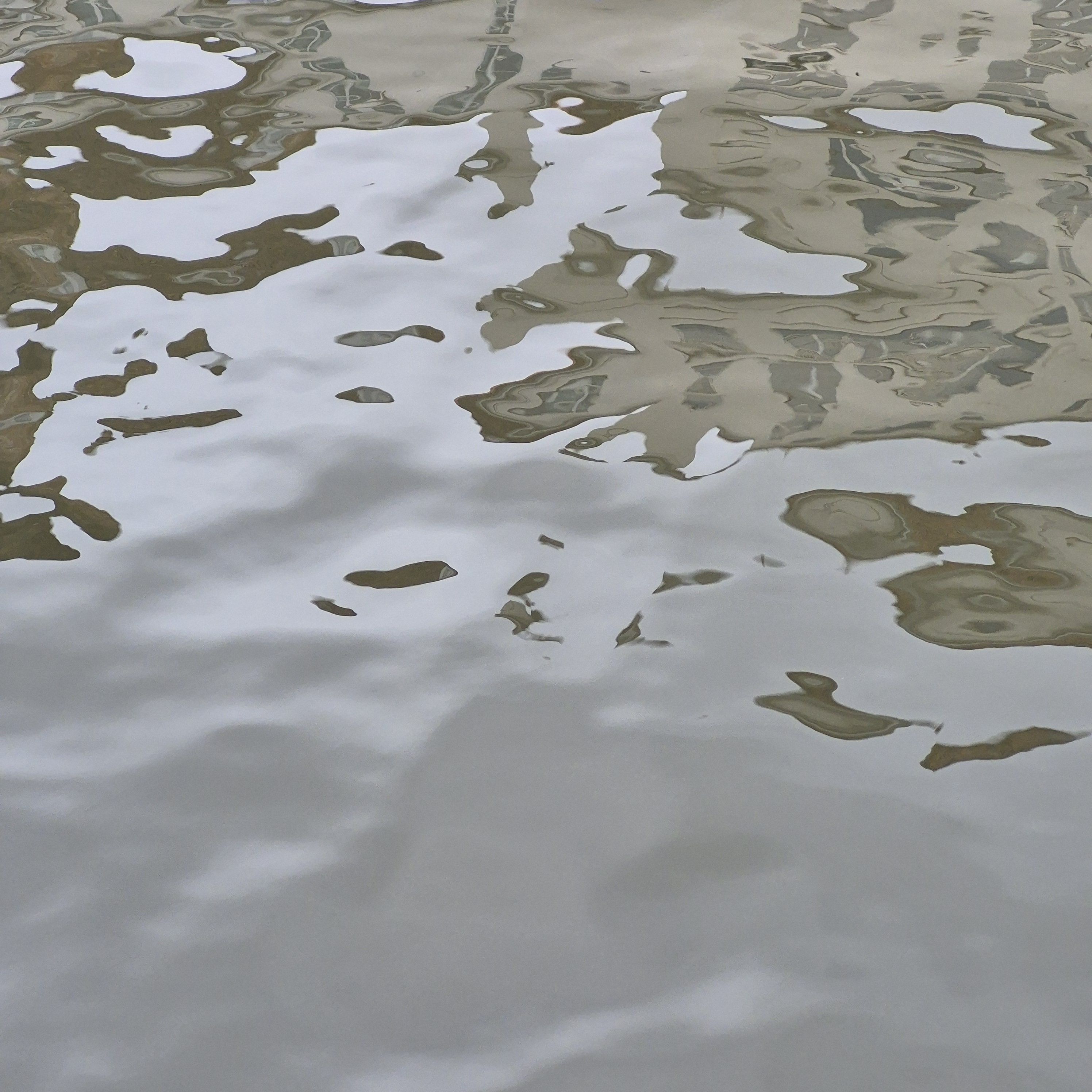 Stille Wasseroberfläche mit Spiegelungen von Häusern.