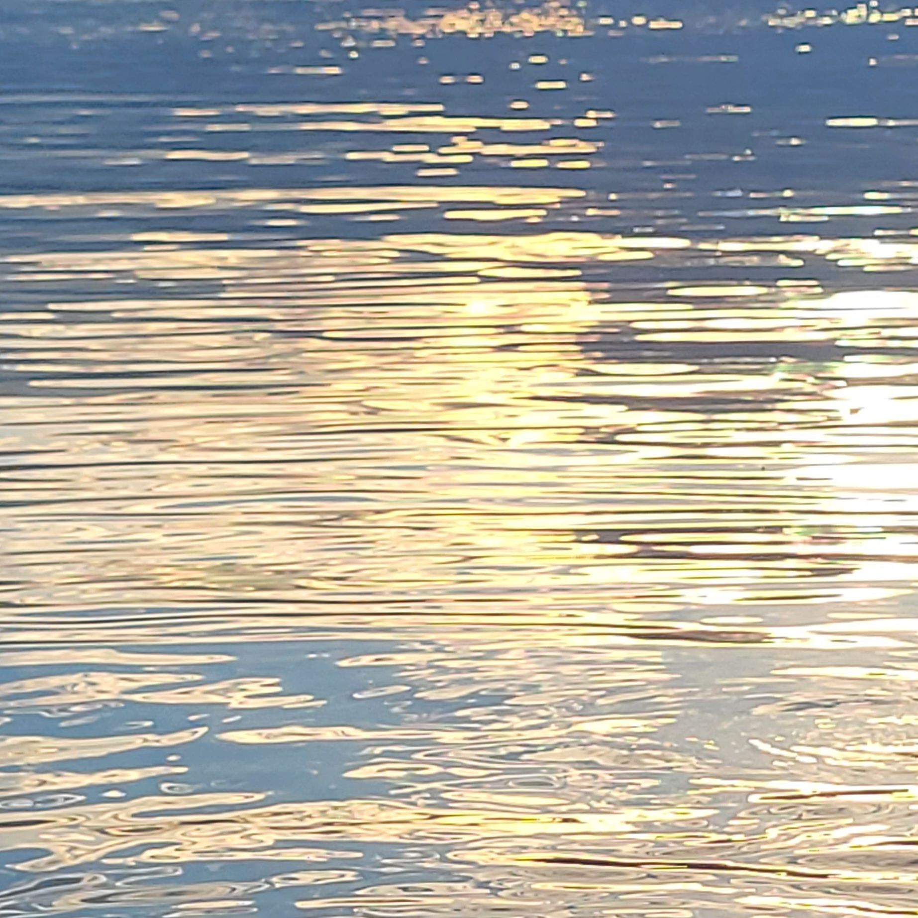 Lichtreflexionen auf einer ruhigen Wasseroberfläche.