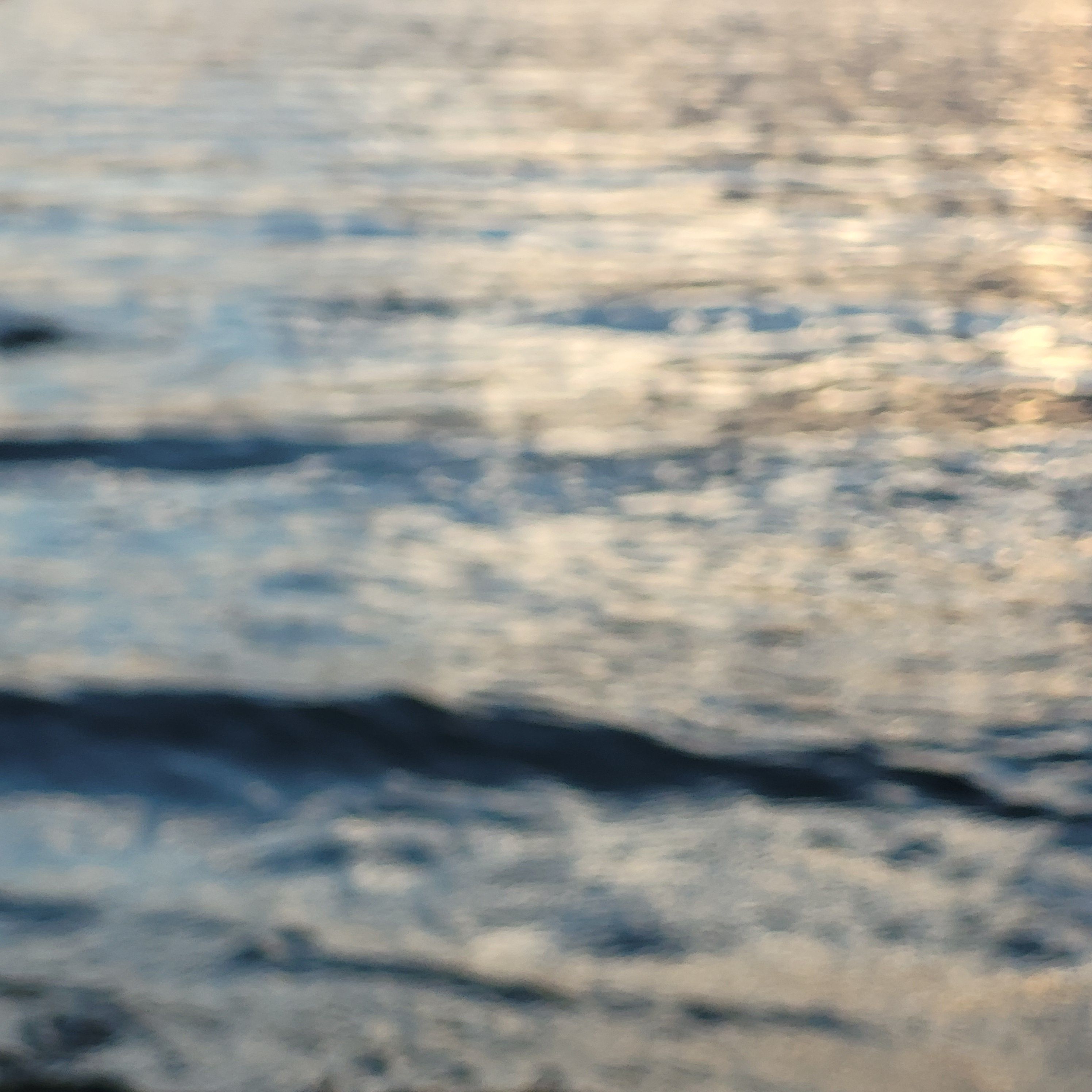 Ruhige Wasseroberfläche mit sanften Wellen und Lichtreflexionen