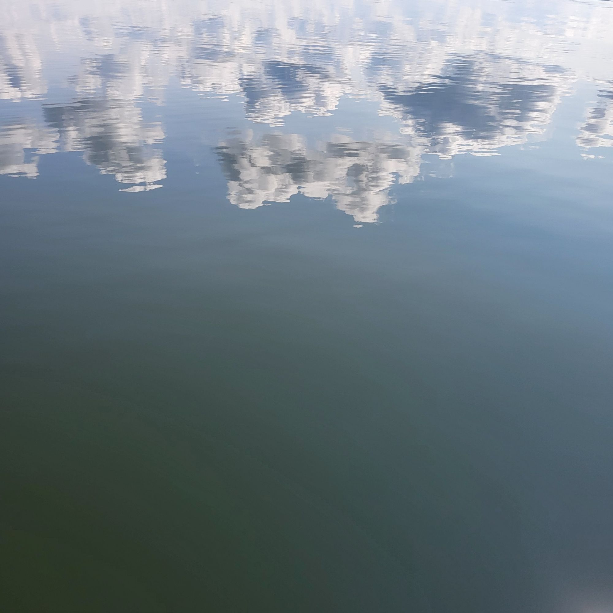 Wolkenspiegelung auf spiegelglatter Wasseroberfläche.