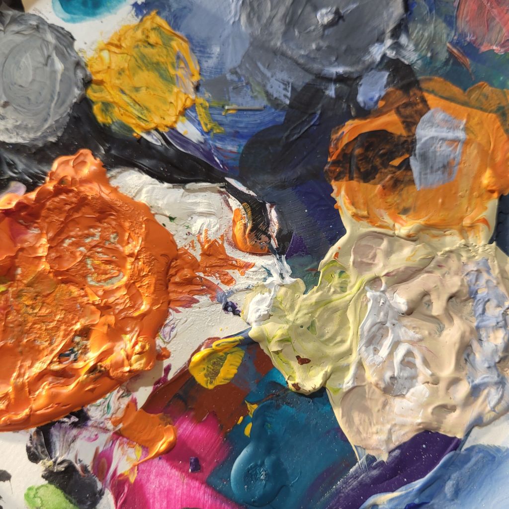Diverse Farbrest von orange über weiß bis blau einer angetrockneten Pallette von Acrylfarben.